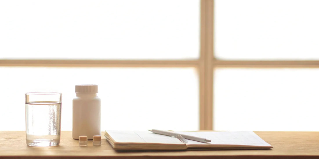 Gut supplements, a glass of water, and a notebook for tracking potential side effects.