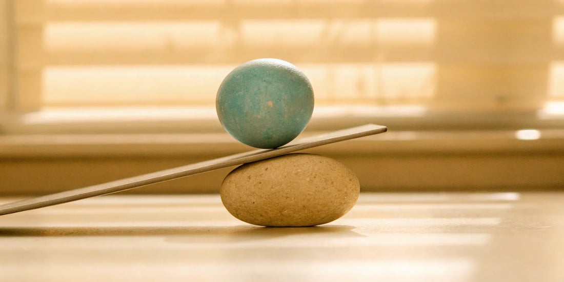 A blue sphere in perfect balance on a plank and stone for achieving mood balance without side effects.