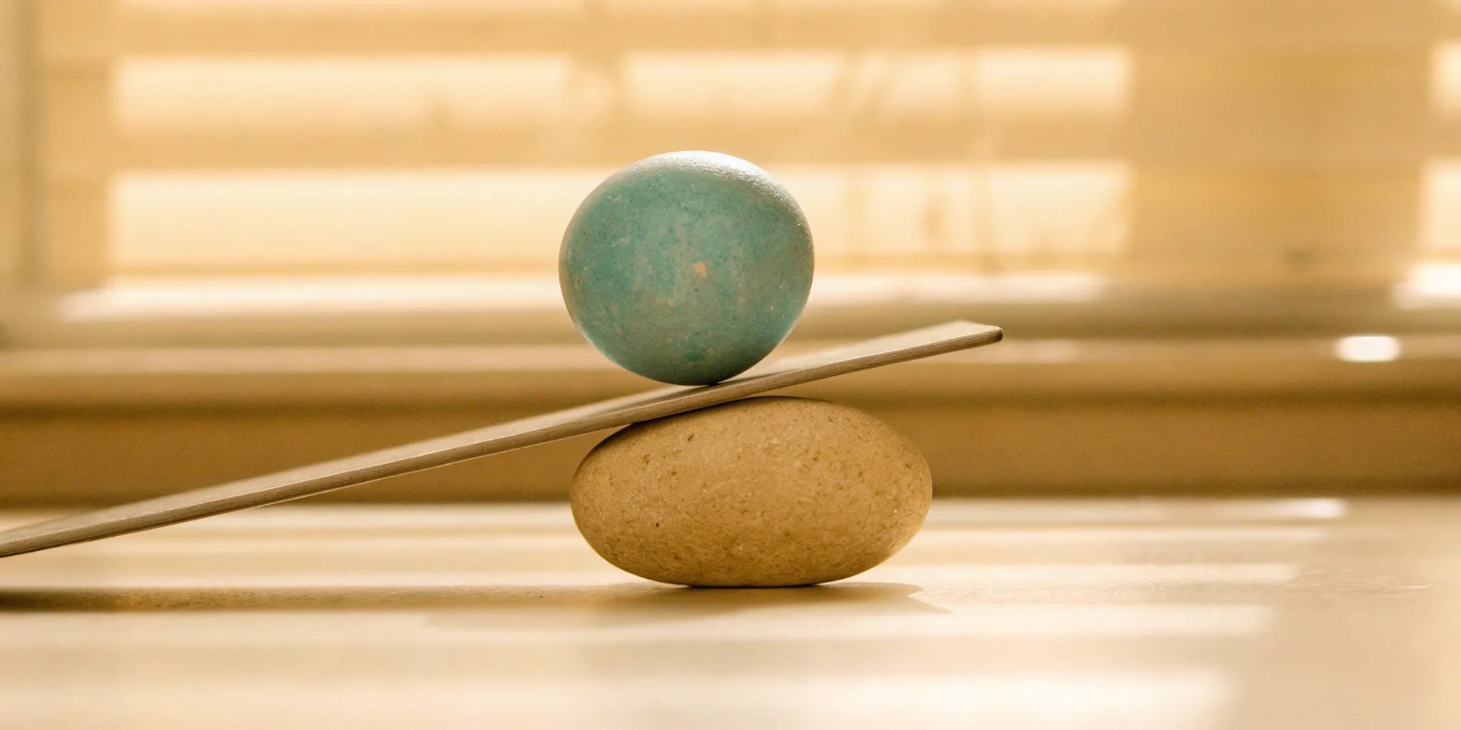 A blue sphere in perfect balance on a plank and stone for achieving mood balance without side effects.