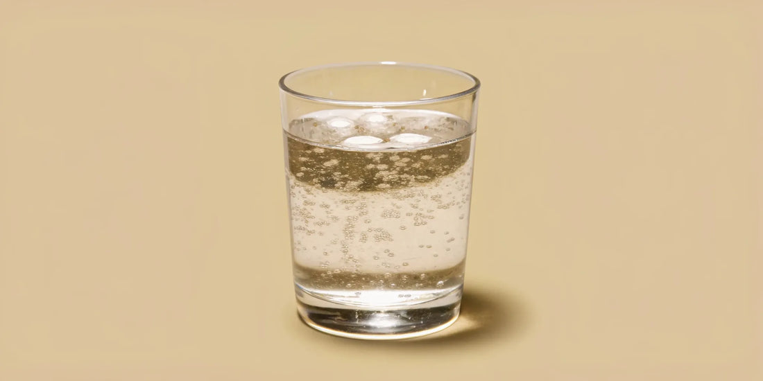 A minimalist aesthetic glass of sparkling water with bubbles under gentle morning sunlight