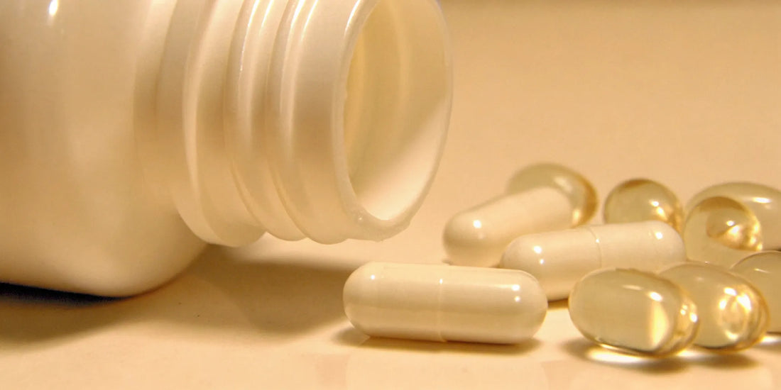 Postbiotics supplements in white capsules spilled out of a bottle.