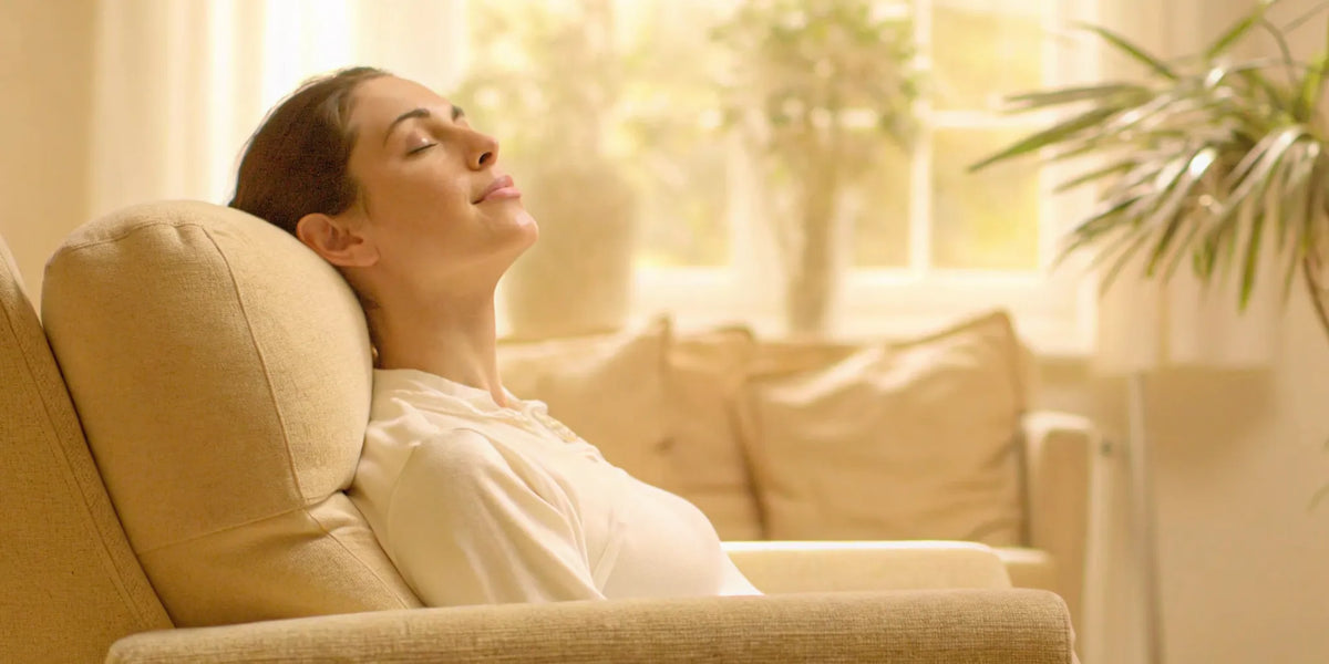 Woman relaxing peacefully in a bright living room with plants, representing calm and gut-brain wellness