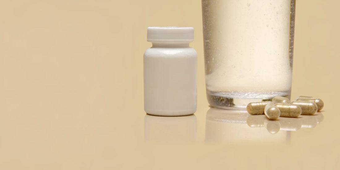 A bottle of probiotic supplements for digestive health with capsules and a glass of water.