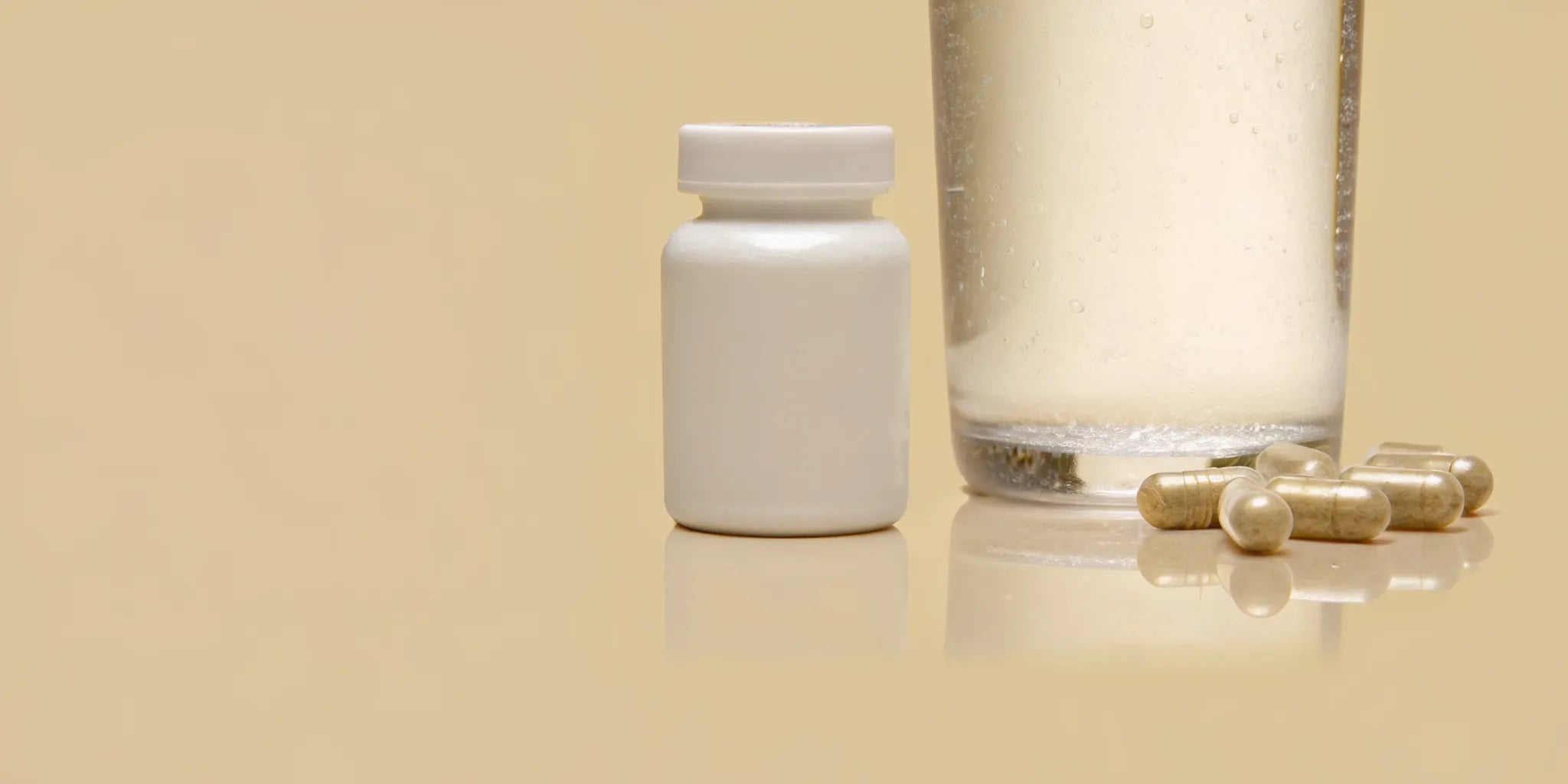 A bottle of probiotic supplements for digestive health with capsules and a glass of water.