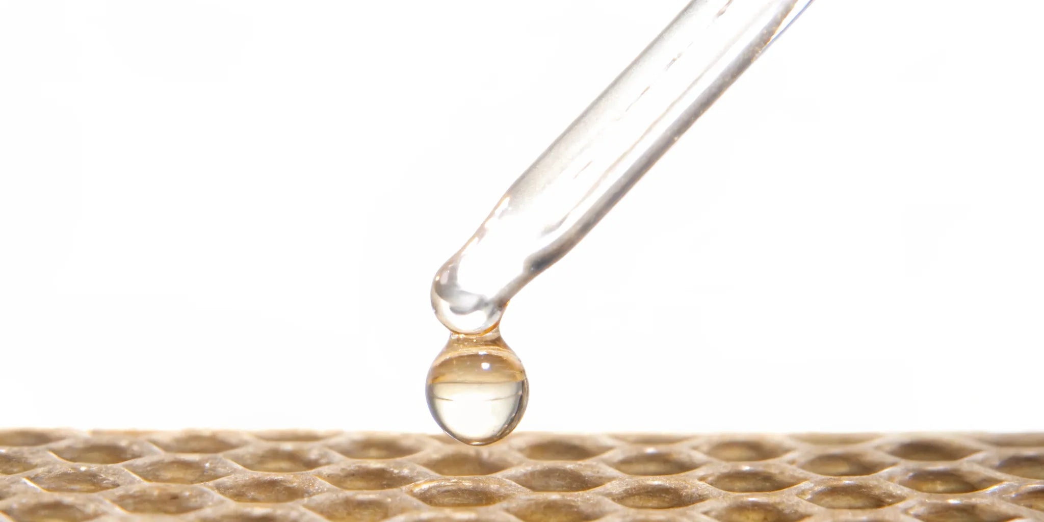 A dropper releasing a liquid postbiotic complex onto a honeycomb structure.