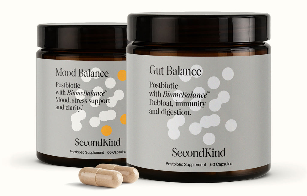 Two brown jars of the Gut and Mood Balance Bundle by SecondKind, each containing 60 postbiotic capsules, highlight the gut–brain axis connection. Two beige capsules are placed in front of the jars.