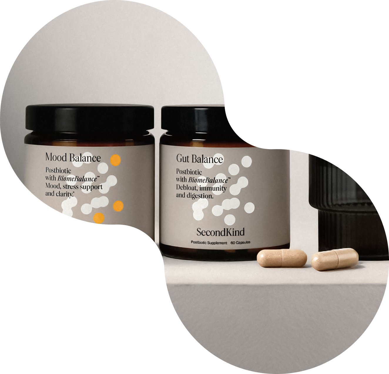Two supplement jars labeled Mood Balance and Gut Balance by SecondKind, along with two beige capsules, are arranged on a clean, light-colored surface with a minimalist, modern background design.