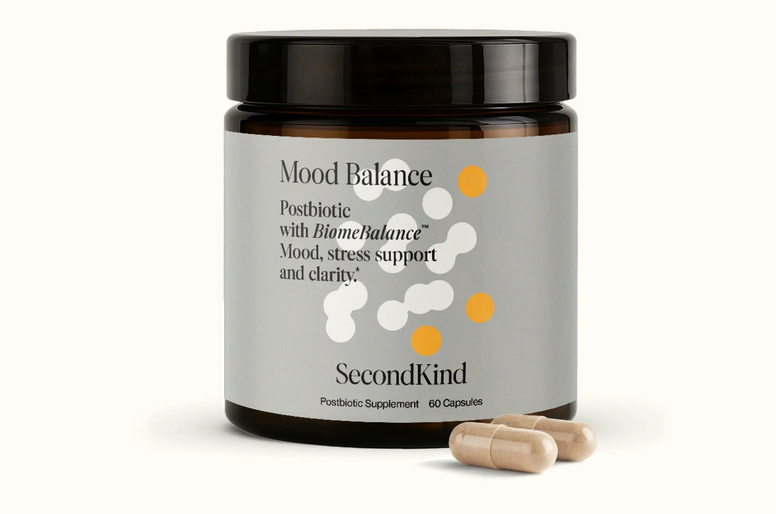 A brown jar labeled Mood Balance by SecondKind, containing 60 postbiotic supplement capsules for mood, stress support, and clarity. Two beige capsules are placed in front of the jar.