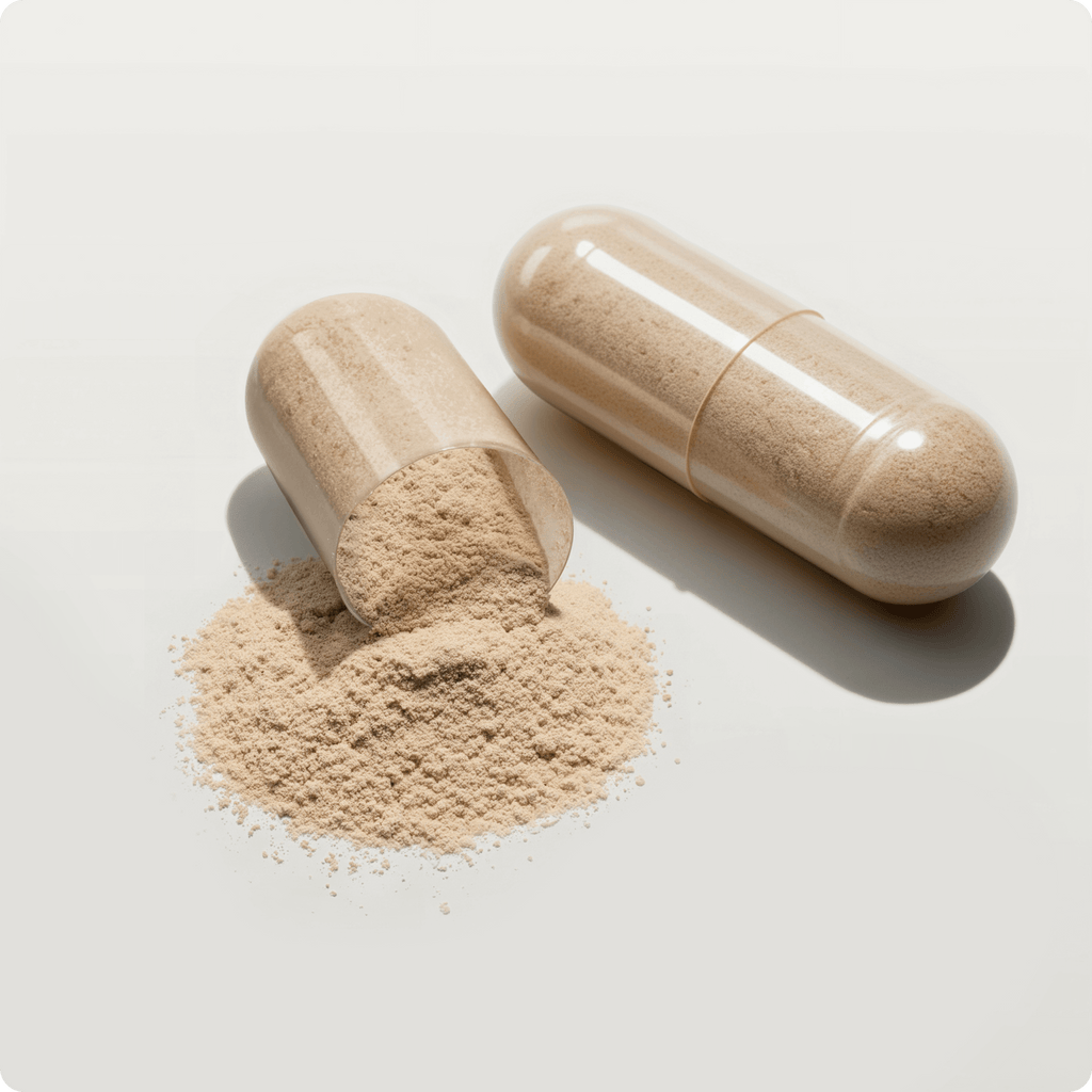 A large clear capsule of Gut Balance, filled with beige postbiotic powder, is partially opened with some powder spilling onto a white surface to help support digestion.